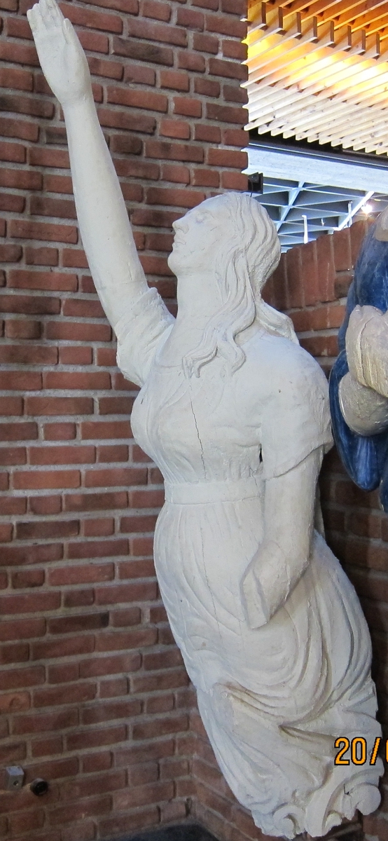 Kvinnefigur med høyre arm hevet, venstre underarm mangler.