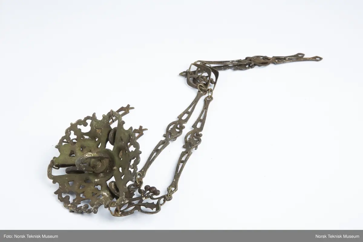 Lysekrone / hengelampe i metall for sju lys (seks lys + ett i midten). Lampa er ødelagt og i mange deler, oppheng, løse pæreholdere, glassbeholder, kuppel etc.