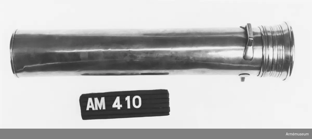 Samhörande nr är 294-299, 321-350, 400-448 (410-411).
Mässingfodral t trumpinnar, Danmark.
Nyttjades i danska hären 1810-1851. Utgick enl. armébefalig 1851-02-03. Gåva av danske CA generallöjtnant Otto Blixenkrone-Moeller vid hans besök i Sverige sep 1972. Locket är fäst vid burken med ett gångjärn i mässing. Två st. handtag sitter strax under locket, även de i mässing. På danska: Messinghylster till trommestikker.