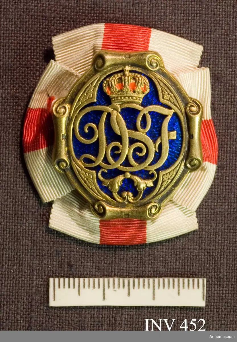 Brosch av förgylld silver och blå emalj. Med drottning Sophias initialer "D S F" krönt med en kunglig, sluten krona. Kronan är fylld med röd emalj.

Bokstävernas höjd: 14 mm. På ramen kartuscher.

På baksidan är broschnålen genomstucken ett band i rött och vitt ripsband som är förenad som en rosett och synlig från framsidan 7 mm.

På baksidan stansat "G.Möllenborg Kongl.Hovjuvelerare Stockholm.