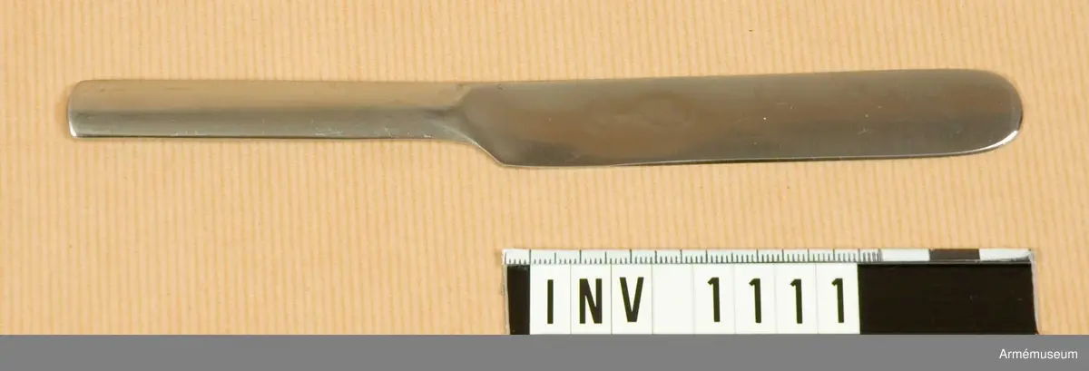 Samhörande nr är 1074-1129, (1109-1111).
Kniv m/1929.
Utförd i ett stycke och saknar egg. Liksidig. På bladet står "GENSE ROSTFRITT" samt en kunglig, sluten krona. Kniven förvaras under transport och förvaring instucken i skeden tillsammans med gaffeln. Har tillhört mob.utrustning vid Armémuseum.
