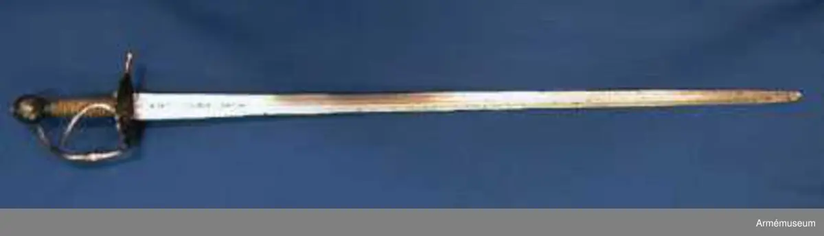 Klingan märkt med P-stämpel och "(CO)". Bredd vid fästet: 34 mm.

Fästet med upp-/nedvänd, äggformig knapp m icke ursprunglig låg nitknapp. Kavellindning av snodda mässingstrådar i reglementsenligt mönster är av senare datum. Randad, flat, svärtad parerplåt; något mindre på insidan än på utsidan. Dess kant är svagt runduddad och den undre sidan har en ornering i form av radialt ordnade ränder. "Nr: 191" inputsat. Handbygeln m förtjockning på mitten är intappad i knappen. Från parerplåten utgår en svängd, yttre sidobygel och ansluter till handbygelns övre del. Parerstången nästan rakt utstående m ett droppformigt avslut. Från parerplåtens insida utgår vertikal tumbygel. 

Klingan tveeggad m flat ås och hålslipning på bägge sidor. I dessa äro inslagna otydliga bokstäver "(CO)" och P-stämpel.