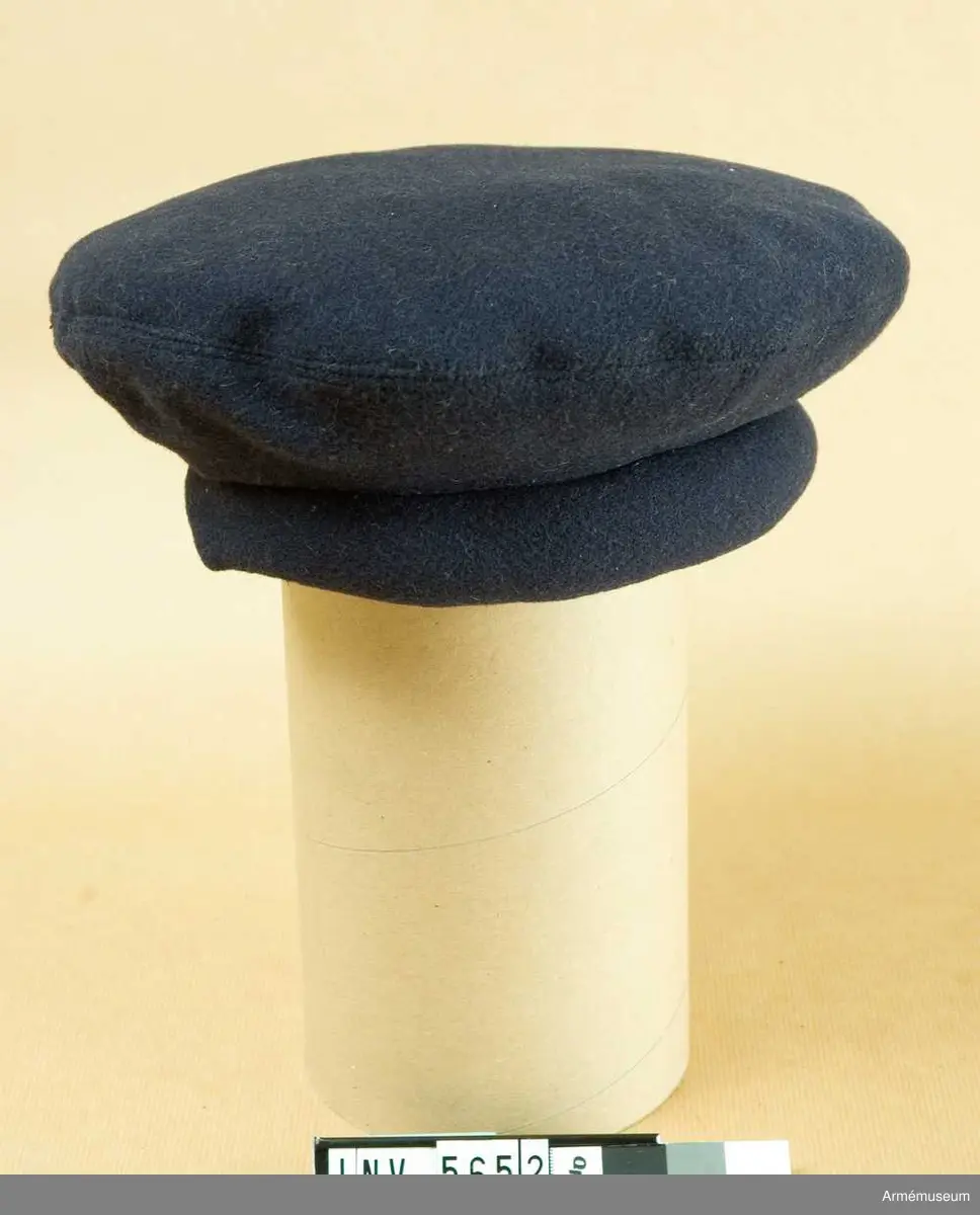 Stl 52. Av mörkblått kläde med s k svulst i kanten. Märkt i  fodret "1944 ACB" tre kronor. Inköpt f tio kronor av  FFV,  Allmateriel AB, Solna.Enl 1925 års försvarsbeslut organiserade år 1928 vid Göta livgarde en stridsvagnsbataljon. Denna uppdelades enl 1936 års försvarsbeslut i två pansarbataljoner, en vid vardera Skaraborgs och Södermanlands reg. Den 1/10 1942 bildades ett självständigt truppslag, pansartrupperna, småningom bestående av fyra reg.Se "Svenska arméns regementen, regementstraditioner" av Carl  Herlitz.