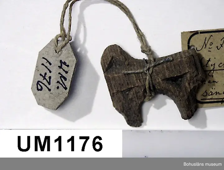Fragment av större träföremål i ek, ornamenterad på framsidan i plattskärningsteknik. 
Enligt påskrift på äldre, vidhängande föremålsetikett: "Stycke av Ornament från Gustaf Vasas träsäng."
Ur handskriven katalog över Uddevalla Musei Historiska Samlingar, svenska avdelningen, yngre föremål upprättad  år 1916 av Knut Adrian Andersson, intendent från 1 oktober 1915:
"No 56 = (F:26 i 1869 års katalog av G. Brusewitz)
Stycke av trä-ornament från
Gustaf Wasas säng. Skänkt 1863 av Gustaf
Hagman i Uddevalla".

Ur handskrivna katalogen 1957-1958:
Stycke av träornamenet
Mått: 3,7 x 3,4 x 0,7 cm; (skall vara fr. Gustav Vasas säng).

Litt.: Utställningskatalog "Ärva och Förvärva Vårda eller Fördärva?", Stiftelsen Läckö institutet, 1995.
Utställningskatalog "Guide till svenska folkets kungaminnen", Livrustkammaren 2003.