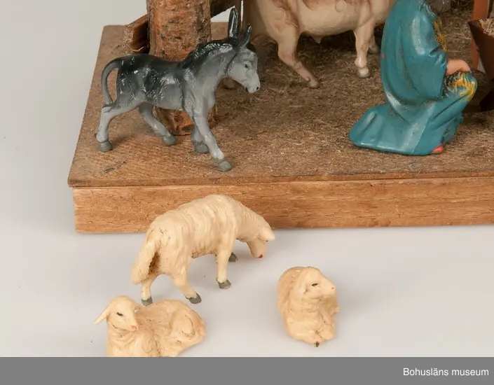 Stall med halmtak, trästolpar samt golv och vägg av masonite. Märkt UM19818:1
18 st figurer tillhör julkrubban. De är märkta UM19818:2.
Krubba, Jesusbarnet, Maria, Josef, en herde, de tre vise männen, en åsna, en oxe, tre liggande får, fem stående får varav ett betydligt större.
En av de tre vise männen märkt: Germany
Elastolin brukar denna typ av plastisk massa benämnas - egentligen ett  tyskt inregistrerat varumärke på en kompositmassa.