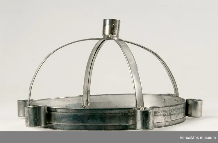 Luciakronan ställbar med oval nederdel med sex nitade ljushållare, från nederdelen utgår två tvärgående band i bågform. Där banden möts finns en sjunde fastlödd ljushållare.