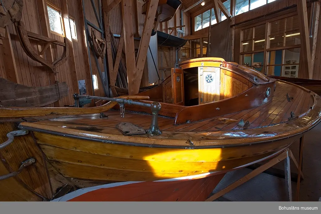 Spetsgattad. Klinkbyggd. Bord och spant av ek. Borden är nitade.
Däck av oregonpine. Ruff av mahogny och oregonepine (taket). Masten (H 10,3 m) och bommen (L 3,1 m) är gjorda av oregonpine.
Tidigare var båten gaffelriggad men i samband med en ombyggnad 1952 fick hon däck, ruff och en ny modern rigg samt kryssfock och storsegel av bomull tillverkat av Hasses segelmakeri i Göteborg, se UM026494 - UM026495. Se Länkade filer under Tilläggsinformation.
På sittbrunnens sarg sitter en namnskylt i trä; "NYMF".
Ett blått kapell, sprayhood, med två vita stänger från 1980-tal samt en båtshake förvaras i ruffen. Se Länkade filer under Tilläggsinformation.

Båten ägdes på 1930-talet av Karl Otto Jonasson. År 1941 sålde han den till Folke Gunnarsson och Rune Olsson. Fem år senare köpte Folke ut Rune.
Folke var med i Segelsällskapet FRAM i Göteborg. Båten kallades Nymf och hade nr 64 i segelsällskapet FRAM. År 1988 tog Karl-Erik Karlsson över båten.

Enligt Sveriges befolkning 1900 heter båtbyggaren Karl Alfred Fredriksson Stjërn, född i Kville 1857.
 
Litteratur: 
Börjesson, E, Börjesson, L., Dunér, m fl.: Kostern. Segelsällskapet Fram 100 år. 1896-1996. Göteborg 1996.
Sörenson, Reiners: Stjerns båtbyggeri på Galtö. Ur Träbiten nr. 93, Föreningen Allmogebåtar, Göteborg 1996.
Hasslöf, Olof: Svenska Västkustfiskarna, Stockholm 1949, sidan 296 ff,
Fredriksen, Christine: EBBA och NYMF - nöjesbåtar vid Bohuskusten. BOHUSLÄN. Årsbok 1999. Handel och hantverk. Bohusläns Hembygdsförbund och Bohusläns museum, s. 87-104.

Se Bilagepärmen UM26491: Träbiten nr 93 samt information från Segelsällskapet FRAM.
Gaffel och äldre bomullssegel finns el. uppgift från givaren kvar.
Uppgifterna kompletterade 2002-09-06/A-LS

Se Bildarkivet UMFA55001:1, familjebild från 1934 samt UM031358, prispokal från 1935.