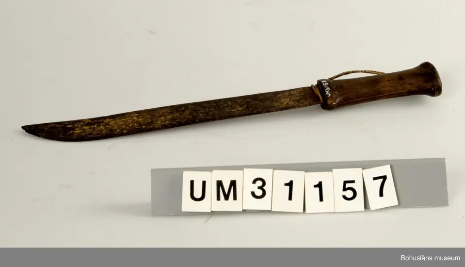 Kraftig kniv med hemsmitt skaft och hemtillverkat skaft av furu. Otydlig stämpel på knivbladet:
SINA (?)
Kniven kallas fläckekniv och har använts under långafiske att öppna långan (fläka upp buken).

För ytterligare upplysningar om Carl Gustaf Bernhardson samt om förvärvet, se UM31100.