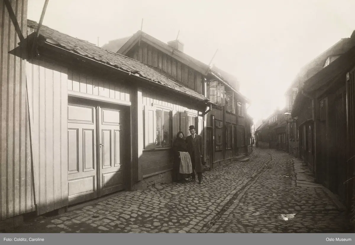 gateløp, trehusbebyggelse, brostein, rennestein, mann, kvinne