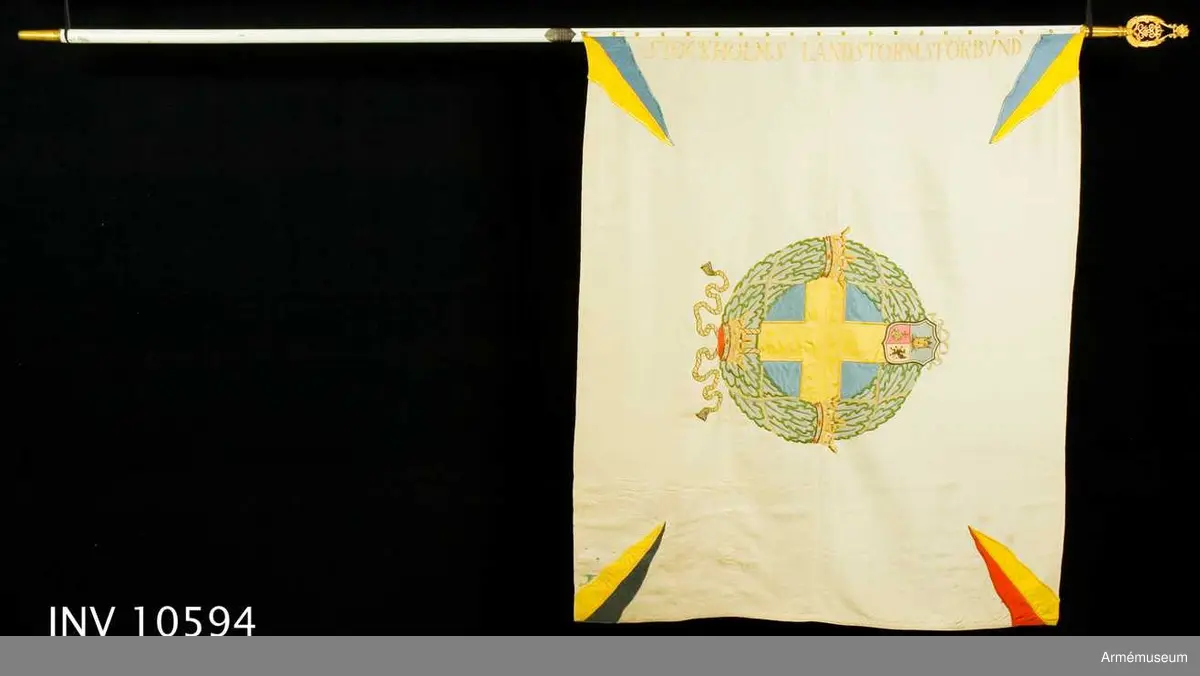 Grupp B I.

Tillverkad hos AB Greta Zachau's Flaggfabrik, Stockholm. Tillverkad och överlämnad till förbundet år 1927. Samhörande spets, kravatt, fodral, innerfodral. Höjd 1190 mm vid stången. Från Stockholms befälsutbildningsförbund genom polisassistent  H. L. Colliander.1974: