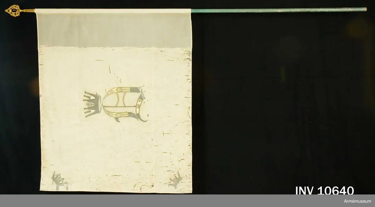Duken vit med i guld broderat anglosachsiskt O under furstlig krona. På tillhörande lapp av äldre modell anges att Visby stads beväringsbataljon erhöll fanan 1832.
