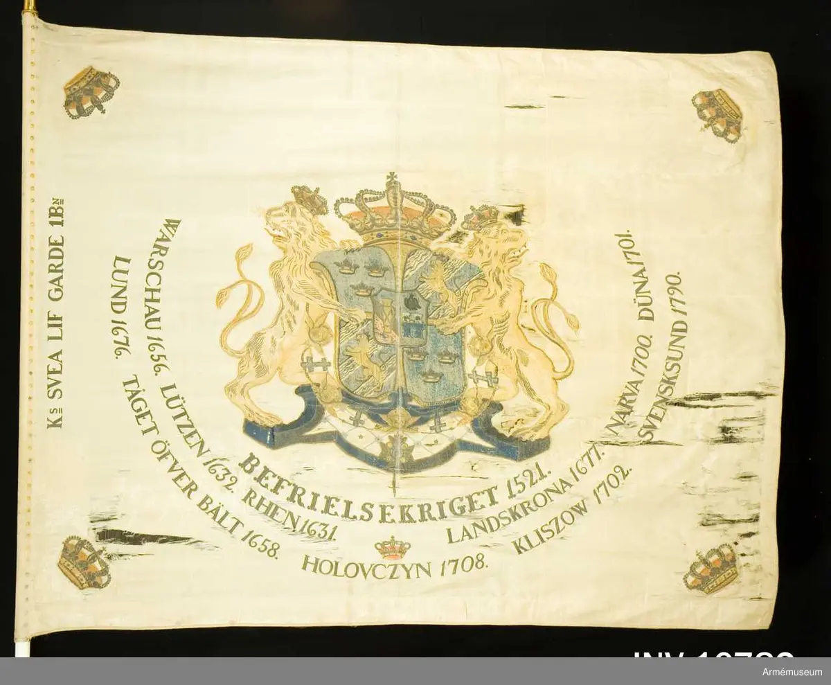 Duk av vit sidenkypert varå broderat lika å båda sidor, riksvapnet omgivet av segernamnen, slutna kronor i hörnen. Kravatt med guldfrans tillhör. Fanstången är vitmålad. Spets med Oskar II:s namnchiffer.