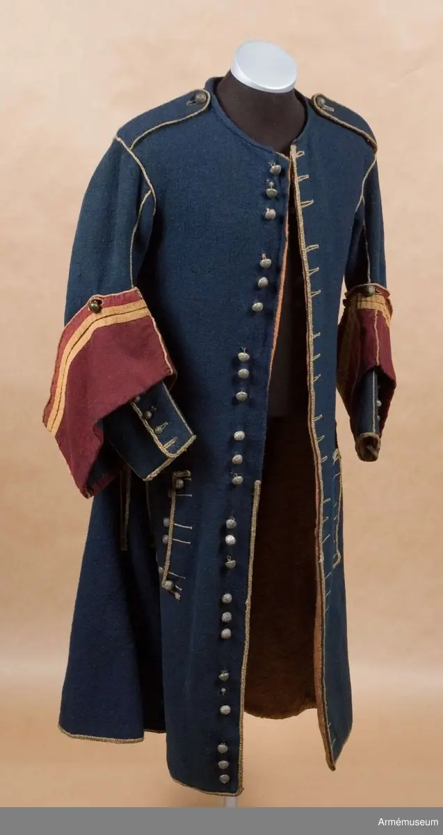 Grupp C I.
Uniformsrock-, Frankrike. Justaucorps, sannolikt 1680-t. Antal knappar i original: Knäppning mitt fram 23 st (ursprungligen 24). Rockens vänstra sida 4 st (urspr 6), den högra sidan 6 st, vänster yttersida 4 st (urspr 6), höger yttersida  3 st (urspr 6). Vänster och höger axel 1 st på var. Vänster och höger ärm 4 st  på var ärm. /AA nov 1986.