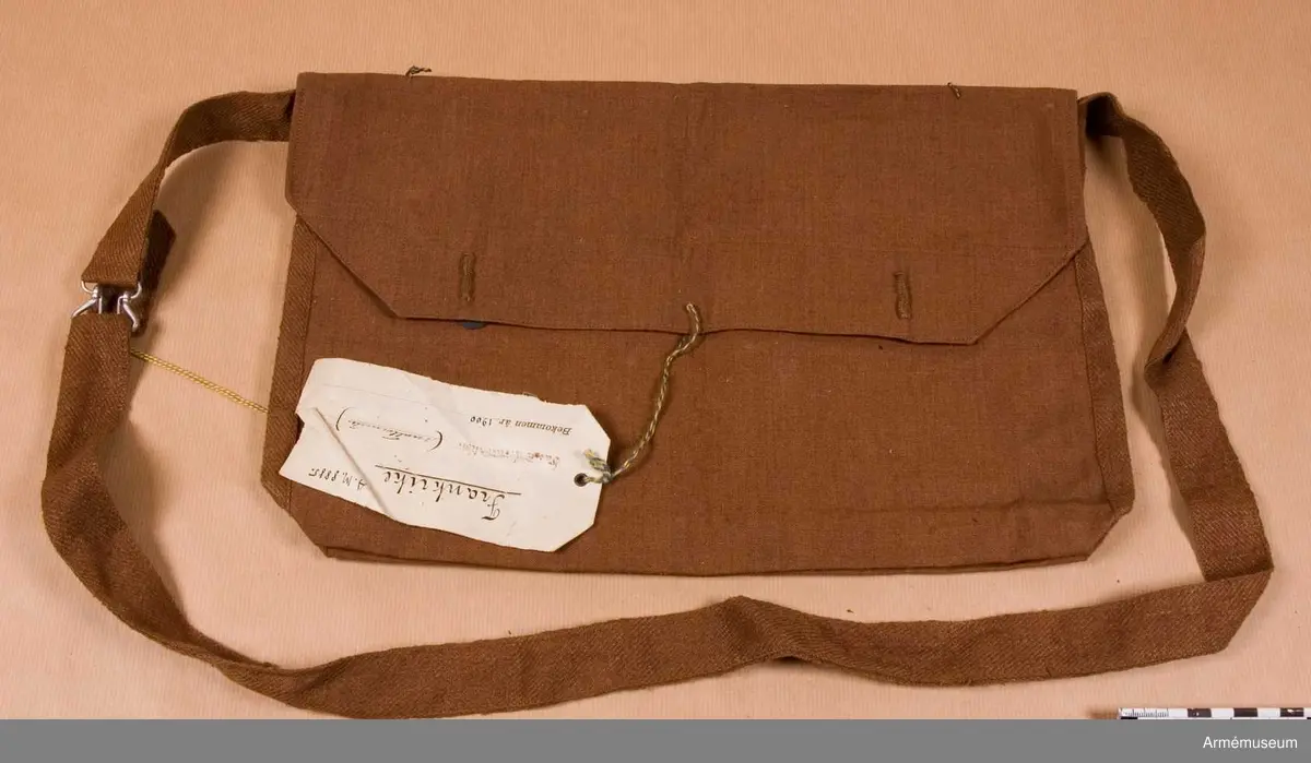 Grupp C II.
Brödväska av brun lärft. Lock som stänges med två knappar av järn med påskrift "Equipments militaires". På lockets baksida finns stämplar 1) "22 Sre. C.O.A.", 2) rund "Paris" -resten oläsligt  samt 3) "3.11.97". Gehäng av brunt bomullsband med spännen av vit metall.
LITT  Le Panorama. Types et Uniformes de 1'Armée Francaise per Edvard Detaille, sida 24. Bild av menig med samma mattornister.
Enligt kapten W. Granberg.