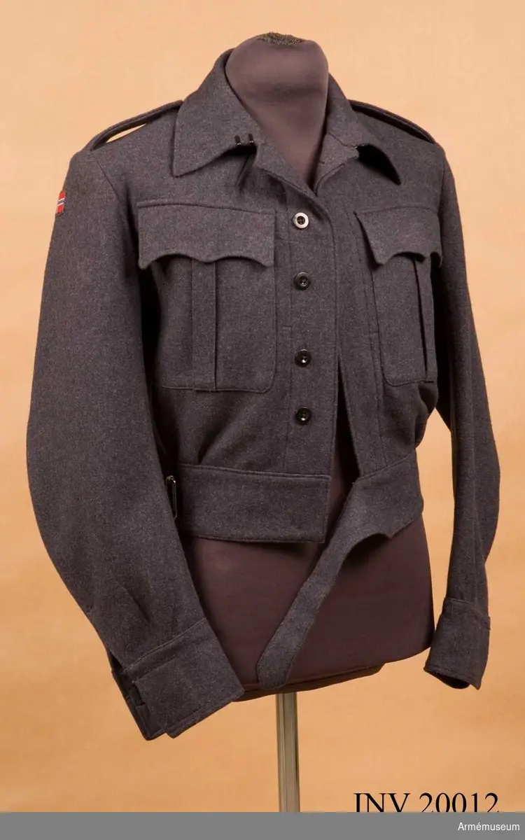 Blus eller kort jacka tillhörande uniform 1943 för manskap vid infanteriet i Norge.

Jackan är sydd av blågrått kläde, och är enkelknäppt med 5 knappar. Längs nedre kanten en 7 cm bred linning av samma kläde med bälte och spännen. Axelklaffar av samma kläde, l:120 mm, b:50 mm. Fastsydda vid ärmsömmarna och fästade vid vapenrocken med svarta plastknappar. Två bröstfickor med motveck, med fasonerade lock som knäpps med tre tryckknappar. Plagget är ofodrat. Infodringar samt två innerfickor är gjorda av mörktgrått bomullssatin. Knappar: På bröstet 5 st, på locken 2 st, vid ärmuppslagen 2 st. Alla är svarta plastknappar. Krage utan slag, liggande, knäpps med två hyskor och hakar. Ärmuppslagen rakskurna med sprund och knäppning. På högra ärmens övre del finns fastsydd tygmärke med norska flaggan. På vänstra ärmens övre del finns fastsydd ett svart tygmärke med ordet "Norway" broderat i vitt.

Grupp C I.