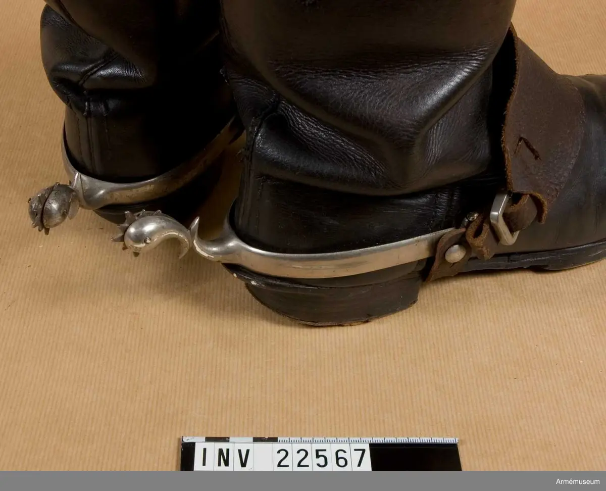 Sporrarna är av förnicklat stål och har en knapp på varje sida med spännen. De har dubbelkrökt hals med tio spetsiga hjul - fem stora och fem små. Remmarna är av svart läder, två för varje sporre. Med remmarna sätter man fast sporrarna. Remmarna som går över vristen har en 7 cm bred läderbit.