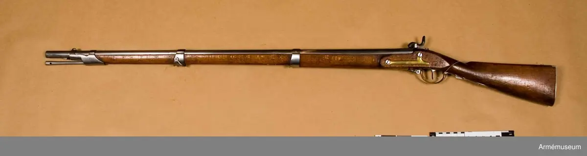 Grupp E II. 

Nominalkaliber 17,5 mm, verklig kaliber 18 mm.
Pipan är rund och blank. Snäckan är stor. Dess antändningskanal är bruten i vinkel och den horisontala grenen tillslutes utåt av en på snäckans utsida placerad, med fyrkantigt huvud försedd skruv.

Framtill på pipan finnes ett båtformigt mässingkorn och på svansskruvsstjärten sitter ett högt ståndsikte. På pipans översida är inslaget BGC= Bestaendig Gevaer Commission (efter 1829) och B - 382.

På vänstra sida står 12.L.I.B.4 C.29 R ( 12:e linjeinfanterieregementet, andra bataljonens 4:e kompani 29).

Låset har svagt kullrigt bleck och är av Kyhls konstruktion, d.v.s. hanen är placerad på bleckets insida. framtill på låsblecket är inslaget B - 382. Stocken synes vara av bok.

Kolven har kindstöd på vänstra sidan.

Pipan fasthålles i stocken av den uppifrån isatta korsskruven samt av tre flata reglar, som gå i häften på pipans undersida och i skodda hål på framstocken. Dessutom finnes ett fjärde häfte för den främre rembygelns skruv, som ävenledes går genom framstocken.

Beslagen äro av mässing och bestå av bakplåt, varbygel, sidbleck, fyra rörkor och näsbleck. 
Den bakre rembygeln har varit fäst vid varbygelns bakre arm.

Laddstocken är av stål. Den får nog anses vara konisk, och har visserligen stort huvud i den ena änden, men tjockleken tilltager koniskt mot den andra, som dock ej är så tjock som laddstockshuvudet. 
Modellbeteckning enligt kapten Stöckel.//J. Alm 1937.