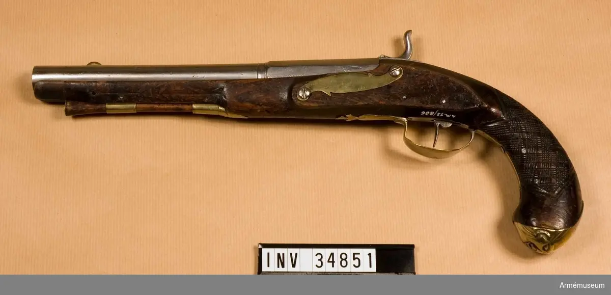 Grupp E III.

Pistol med slaglås. Ändrad från flintlås.

Pipa med åttkantigt kammarstrycke, beslag av mässing och laddstock av trä. 

På kolvhalsen ett skuret rutmönster som antagligen inte är ursprungligt.