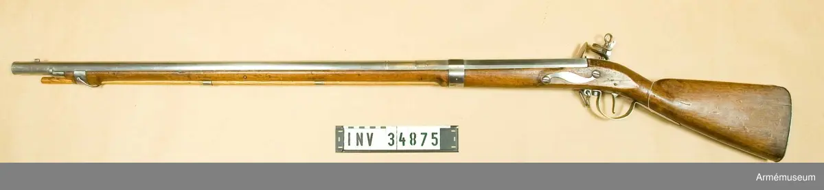 Grupp E II.

Projekt för infanteriet; av Blix i Söderhamn 1690-talet.

Kammarstycket är 31,4 cm långt, baktill åttkantigt, men framtill på en längd av 2 cm sextonkantigt. Det avslutas längst fram av en insvarvad och en upphöjd rand. 4,7 cm framför den sistnämnda på åter ett par dylika ränder kring det runda, långa fältet och 0,5 cm längre fram åter ett par. Ett kraftigt avlångt korn sitter 4,2 cm bakom pipmynningen och längst fram på svanskruvsstjärten finns ett ovanligt kraftigt, lågt ståndsikte. På kammarstyckets översida framför  siktet finns en kronstämpel och siffran 2 och på vänstra sidan sitter en egendomlig stämpel, vilken ser ut som ett monogram mellan 2 och C. På pipans undersida 7,8 cm bakom mynningen finns en kraftig, skarpkantig fläns eller klack, vilken på båda sidor blir lägre uppåt och som går upp på pipan bägge sidor litet högre än vad framstocken gör. Pipan har 3 häften och korsskruven går nedifrån.

Låset har varhake, Blecket är kullrigt samt baktill utdraget i en spets. Hanhalsen är baktill plan och läppskruvsringen har en diam, av 1,9 cm. Pannskruven ersättes av en nit, eldstålsfjäderns skruv går utifrån och samma fjäders bukt går framför den främre låsskruvens ände. Pannstjärten är kort. På bleckets utsida står "M. Blix Söderhamn".

Stocken är av al och har kräva. Framstocken slutar 8,5 cm bakom pipmynningen. Stocken har varit spräckt i kolvhalsen, men är nu hoplimmad.

Järnplåtsbeslagen bestå av bakplåt, som fasthålles av stift; stor varbygel, vars bakre arm fasthålles av två stift och vars främre, som längst fram är utbildad tlll en ögla, fasthålles av korsskruven; kort avtryckarebleck, som fasthålles av 2 stift; ett 2,6 cm brett järnband, som går kring pipans och framstockens 22,9 cm framför pipans bakre ände; ett platt, s-formigt sidbleck; två släta rörkor; ett krävbeslag om 2,3 cm bredd samt ett näsbleck av samma storleck.
Den nedre rembygeln är fäst i varbygeln ögla, men den främre, u-formiga, fasthålles av en skruv, vilken går genom krävan och krävbeslaget.

Laddstocken är av ask och saknar skoning.