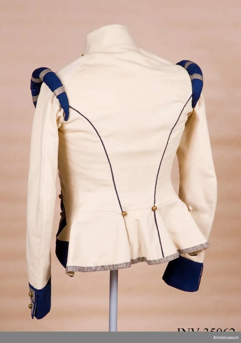 Rekonstruktion av jacka m/1781 för officer vid Lätta livdragonerna.
Jackan är sydd av vitt kläde med kragspeglar, bröstrevärer, axelkarmar och ärmuppvik i mörkblått kläde. Passpoaler av blått kläde i ryggsömmar och främre delsömmar på ärmarna.
Den är dekorerad med metallgaloner på bröstrevärer, axelkarmar och ärmuppslag, och har 16 icke funktionella kulknappar av mässing fram, samt 2 i varje ärmslut och 2 vid ryggslutet bak.
Mitt-fram-linjen är kraftigt svängd, och framstyckena är vadderade över bröstet. Jackan stängs mitt fram samt i ärmsprunden med hysk och hake. 
Den är konstruerad med avskärning i midjan, samt insnitt fram. Separata sidstycken. Skört utan slits bak.
Axelkarmarna är vadderade och står rakt upp.
Jackan är helfodrad med vitt bomullstyg.

Plaggets skärning och sömmar, de vadderade axeltungorna, de djupt skurna bröstrevärerna, uppviken, fodret m.m. indikerar ganska tydligt att den är tillverkad senare, troligen under sent 1800-tal. Även tygkvalitéerna indikerar en yngre datering.