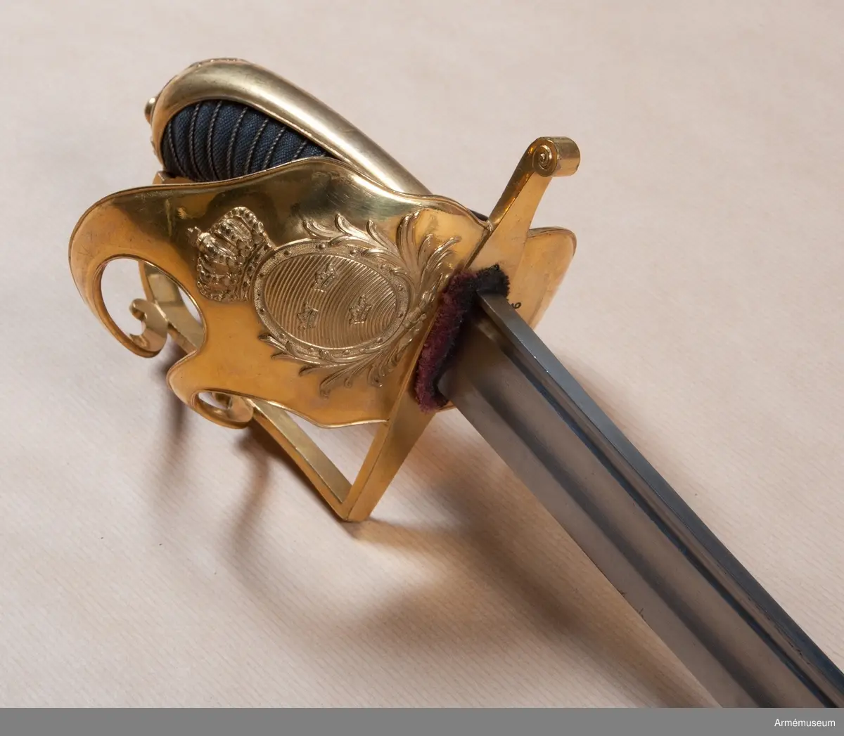 Klingbredd upptill 33 mm. Klingan är krökt och eneggad. Längs ryggen har den en blodrand och framför den en grund skålslipning. Blodranden slutar ungefär 28 cm ovanför udden till blodrandens slut är klingan slipad med egg även å ryggsidan. Fästet är av förgylld mässing. Kaveln är klädd med svärtat fiskskinn, och kring den går en spiralräffla 15 varv. Kaveln har baktill ryggbeslag, som upptill övergår i en låg kappa, vilken pryds med kraftigt ciselerat ornament i form av en stiliserad lagerkrans, vilken omger den lilla fasonerade nitknappen. Parerstången är rak samt har fyrsidigt tvärsnitt. Baktill avslutas den av en nedböjd knapp, vars kanter är ornerade med ciselerade spiraler. På parerstångens övre sida är siffran 3 inslagen. Från parerstångens främre ände utgår handbygeln i rät vinkel. Handbygeln har fyrsidigt tvärsnitt blir bredast framför kappans främre kant. På yttersidan finns en stor uppböjd parerplåt, på vilken finns en krönt oval sköld med tre kronor. Skölden omgives av stiliserade palm- eller lagerkvistar, allt i sicilerat arbete. Från parerplåtens övre spets går en spång, som är böjd i S-form. till handbygeln, som den träffar vid dess övre krök. På andra sidan om föreningspunkten förlängs spången av en liten avrundad utåtböjd flik. En annan liknande spång går fråm parerplåtens främre kant till handbygelns mitt. På innersidan finns en liknande men mindre parerplåt, från vars spets en S-formig spång går till handbygeln, vilken den träffar mitt emellan de ställen, där de båda ytterspängerna förenas med denna bygel. Ryggbeslaget, kappan, handbygelns främre sida, parerplåtarna och alla spänger har längs kanterna en ingraverad rand. På innersidan finns en tumrem, vars ena ände fasthålls av 6 varv av den kring kaveln gående silvertråden och vars ände är instucken mellan kaveln och parerplåten samt är försedd med ett hål, genom vilket tången går.