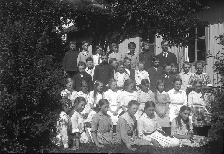 Enligt fotografens journal nr 4 1918-1922: "Folkskolan i Kyrkenorum Här".
Enligt fotografens notering: "Folkskolan Kyrkenorum, lärare Ivar Larsson med elever. (Organist i Norums kyrka)".