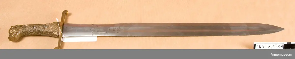 Grupp D II.

Klingans bredd upptill är 44 mm.Klingan är rak och tveeggad. Upptill är den flack, men 120 mm nedanför fästet får den på bägge sidor en ganska smal skål- slipning och blir något bredare. 
Udden ligger i klingans mitt- linje. 
Upptill har den på bägge sidor Maximilian Josefs krönta namnchiffer.
Fästet är helt av brons. Kappan har formen av ett lejonhuvud, vars hårbeklädnad fortsätter ned över hela kaveln. 
Klingan hålls fast av två nitar. Parerstången är rak, har fyrkantigt tvärsnitt, blir bredare kring klingan, avslutas baktill av en nedåtböjd och framtill av en uppåtböjd knapp.
