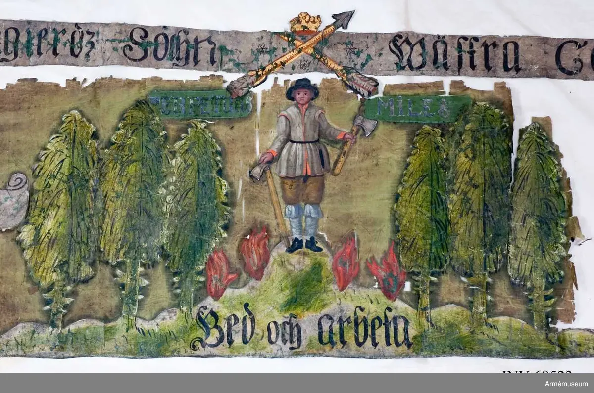 Helt bemålad duk på siden. Troligen från Stora nordiska kriget. Två korslagda pilar krönt med öppen krona (Det vill säga Landskapet Dalarnas vapenbild). En bergsman stående på en sten med fyra flammor omkring. En yxa i vardera handen. Omkring skog. Fragment. Text Överst: GRANGIERDZ SOCHN WÄSTRA COMPAGNIET. Under till vänster FRUCHTA GUD. Längst ner: BED OCH ARBETA. Överst i motivet: PERPETUUS MILES. 