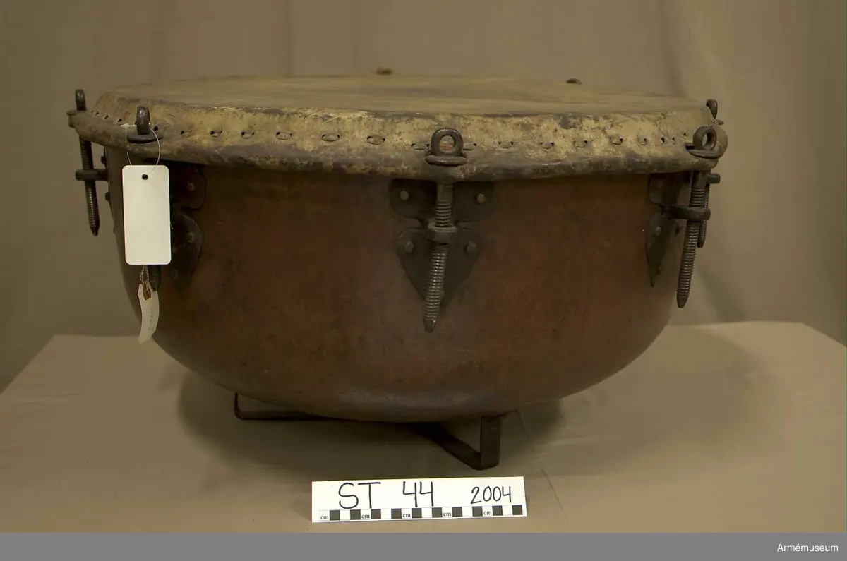 Grupp A.

Tillstånd 2005

Kittel:
Stor, vacker, orange och blank. Två prydliga lagningar där fot fäster i kittel.

Fot: 
Tredelad, stadig. Kan stå.

Spännskinn:
Ljust, fjälligt på mitten. Mycket. litet färgstänk. Efter spännringen fann jag två små trasigheter, annars intet.

Spännring:
Rostig. 

Spännskruv: 
Åtta stycken. Ett rep fastbundet i en av skruvarna.

Skruvfästen:
Åtta stycken. 

Bärrem:
Saknas.