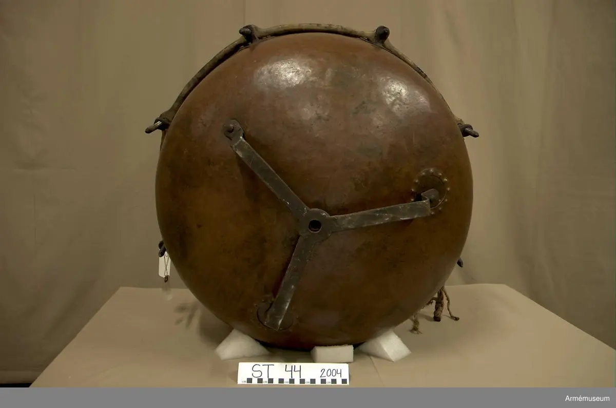 Grupp A.

Tillstånd 2005

Kittel:
Stor, vacker, orange och blank. Två prydliga lagningar där fot fäster i kittel.

Fot: 
Tredelad, stadig. Kan stå.

Spännskinn:
Ljust, fjälligt på mitten. Mycket. litet färgstänk. Efter spännringen fann jag två små trasigheter, annars intet.

Spännring:
Rostig. 

Spännskruv: 
Åtta stycken. Ett rep fastbundet i en av skruvarna.

Skruvfästen:
Åtta stycken. 

Bärrem:
Saknas.