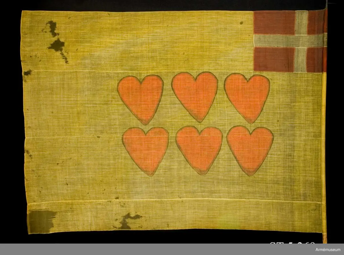 Ylleduk med infällning och målning.

Upptill vid stångsidan infälld Dannebrogen . Mitt på duken målat sex hjärtan i två rader.