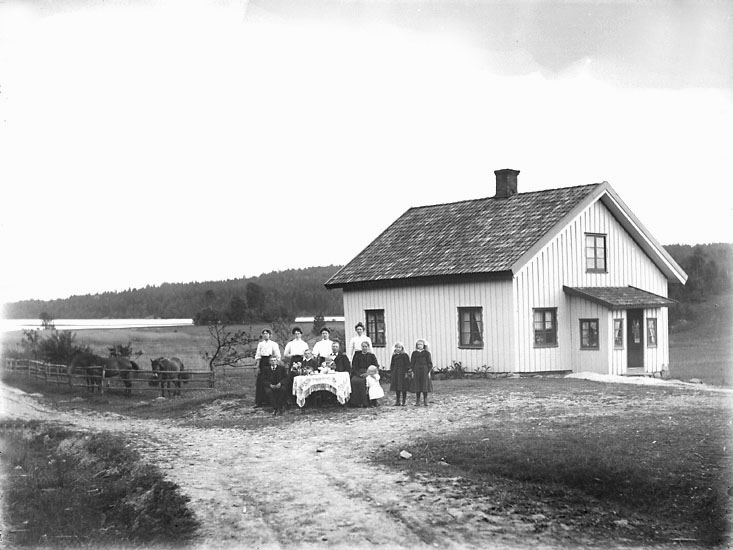 Enligt noteringar: "Familj utanför boningshus, troligen på Nyröd." (BJ)