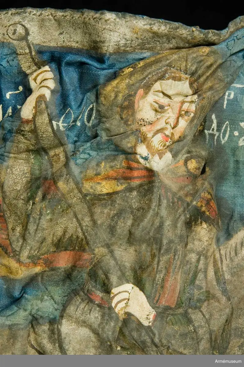 Entungad lansfana. Duk av blå kinesisk sidendamast med målad dekor. I 1703 års inventarium anges motivet vara St Göran men enligt den ryska inskriptionen är det Feodor Stratilat . Rosor och stjärnor av silver. Duken kantad med en silverbård. Strumpa av rött linne.