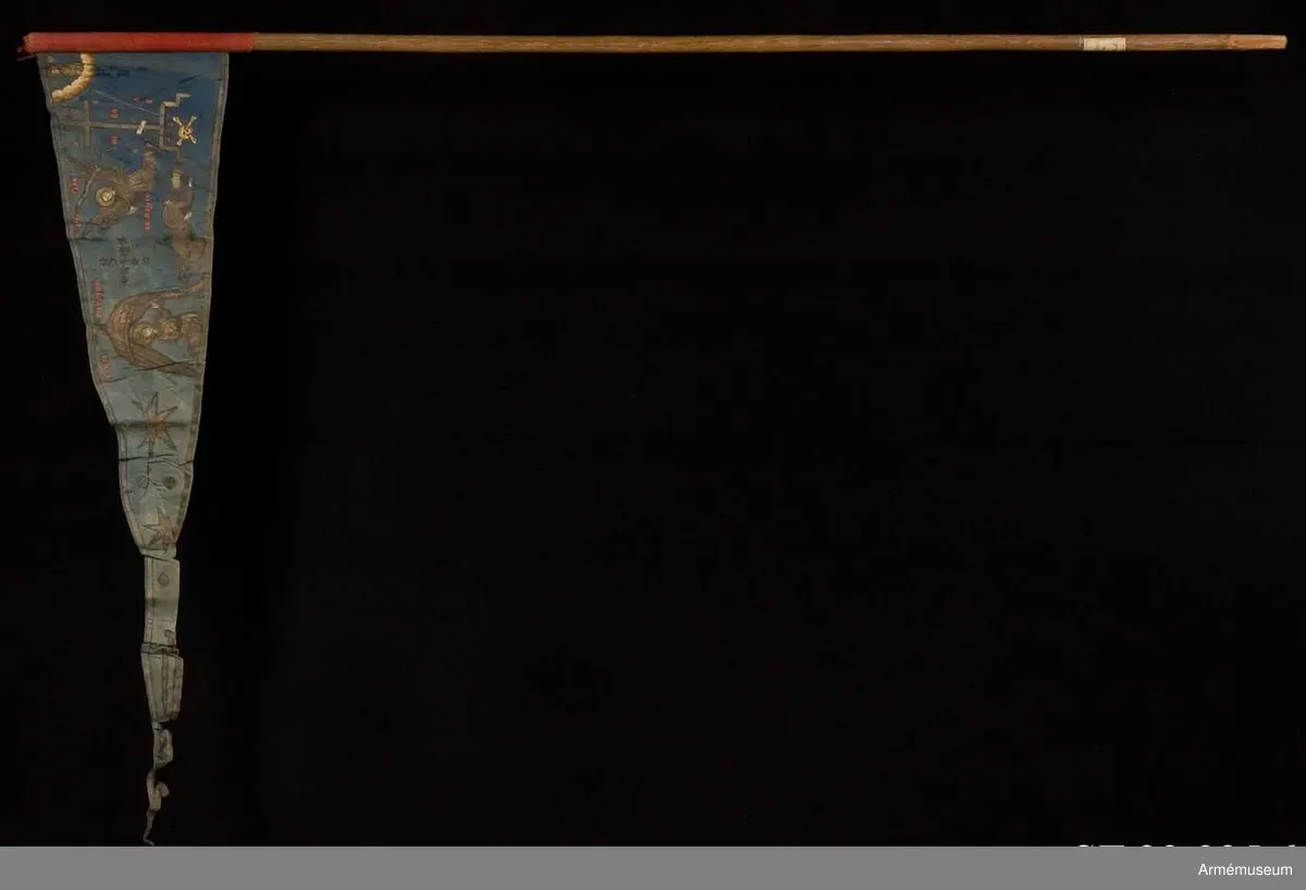 Duk av blå kinesisk sidendamast med målad dekor. Motivet föreställer den romerske kejsaren Konstantins vision av ett kors i skyn kvällen innan slaget vid Pons Mulvius år 312 e Kr mot Maxentius. En ärkeängel med svärd i handen (Gabriel?) svävar över den halshuggne Maxentius. Denna händelse ses som förklaring till att kristna kors började användas på militära fanor. Närmast stångsidan är också ett Golgatakors avbildat. Över detta syns ett moln där Kristus är avbildad. 
Strumpa av rött linne.