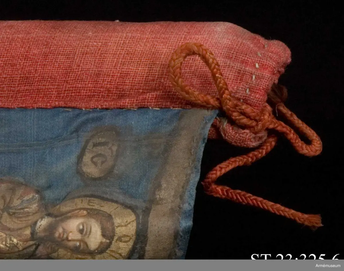 Duk av blå kinesisk sidendamast med målad dekor. Motivet föreställer den romerske kejsaren Konstantins vision av ett kors i skyn kvällen innan slaget vid Pons Mulvius år 312 e Kr mot Maxentius. En ärkeängel med svärd i handen (Gabriel?) svävar över den halshuggne Maxentius. Denna händelse ses som förklaring till att kristna kors började användas på militära fanor. Närmast stångsidan är också ett Golgatakors avbildat. Över detta syns ett moln där Kristus är avbildad. 
Strumpa av rött linne.