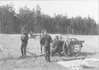 Svea artilleriregemente A 1, klara att skjuta med två 7,5 cm kanon m/1902. I förgrunden filt med korgar, i bakgruden skog med tallar.