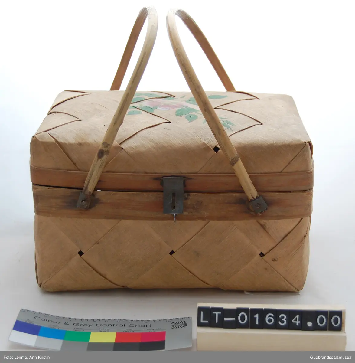 Rektangulær, flettet kurv av furu. Håndtak av bambus, to håndtak kan samles til ett. Med låsemekanisme. Lokk festet til kurv med innslåtte metallkroker.