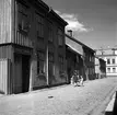 Göta Larsson med barnen Pia och lillebror Åke på promenad utmed Missionsgränd i Jönköping. Det vita huset i bakgrunden ligger på Slottsgatan. I hörnhuset fanns ett bageri.