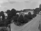 Trekanten (Afzelii plan) och Kyrkogatan, Enköping, vy från söder, ca 1912-1915. Fr. v. prästgården, tingshuset, realskolan (läroverket), kyrkbacken, kyrkan.