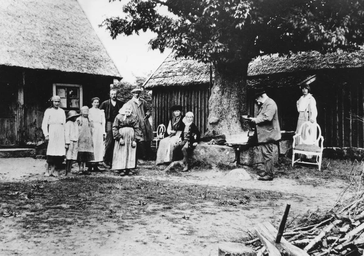 Ateljé. Asige, Björsgård. Fr h Fru Lotti Rääf (senare Jeanneret), f Wallberg. Fabrikör Alfred Wallberg (hennes far), Bengt Rääf (hennes son), fru Lotten Wallberg, Godsägare Axel Rääf (g m Lotti R), Severin Nilsons syster (framför Axel Rääf). Familjen till vänster är släktingar eller grannar till henne. "Nu är det nytt träd och ny stensättning kring det (ur brev från Lotti Jeanneret 10/10 1970).