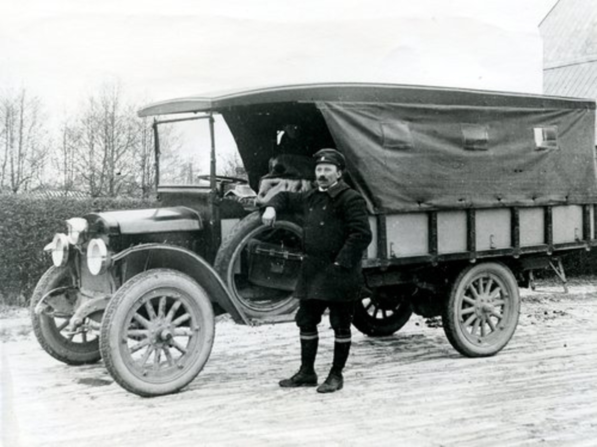 Laholm. Överbyggd lastbil, omgjord till buss på linjen Laholm-Hishult som öppnades 1920. Mannen på bilden är bolagets förste chaufför, Aron Gustavsson.