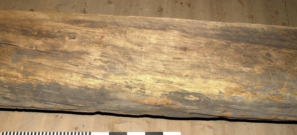 Mastkärna.
Kvadratiskt tvärsnitt. Avsågad/tillputsad i nedre delen efter bärgningen. Andra änden, toppen, är kilformad och spetsigt huggen med liten läpp längs ena sidan. 4 spår för mastjärn utmed långkanterna. Rostfläckar i spåren. Ett urtag på mitten av föremålet. Sprucken. Omkring 30 bulthål. Märkt med blå dymotejp.
Vriden efter bärgning.
