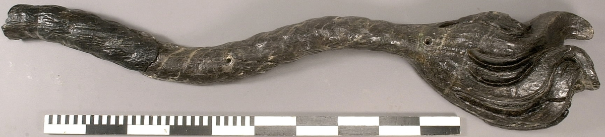 Skulpterad lejonsvans, lagad i rotändan. Svanstofsen är stor och yvig. Svansens baksida är slät.

Text in English: A sculpted lion''s tail, broken off where it was attached to the lion''s hind quarters. The tuft is large and bushy. The reverse side is smooth.