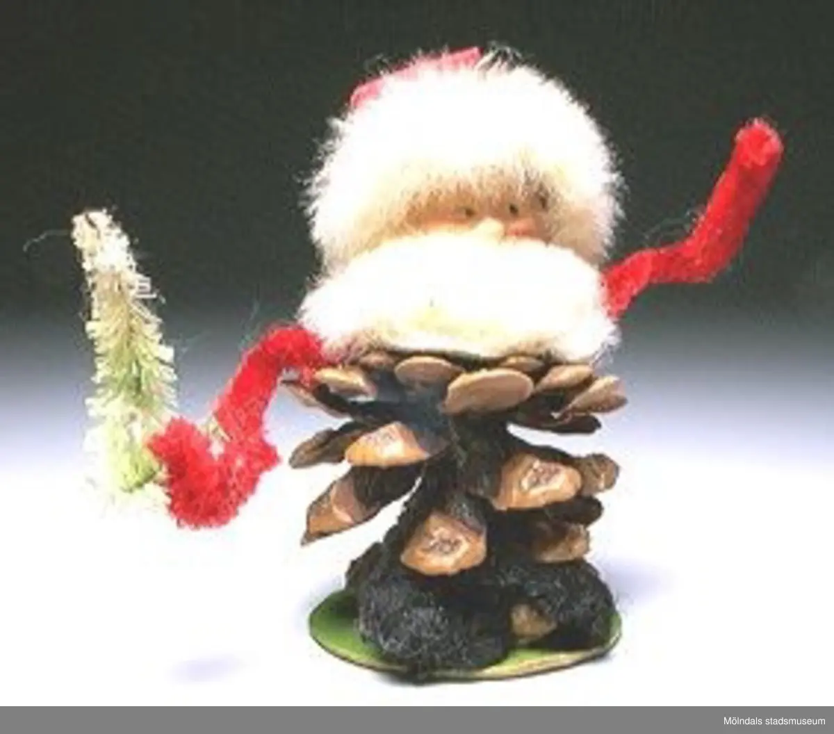 Sex tomtefigurer, tillverkade av flörtkulor kottar och piprensare, en figur består av en stege med två tomtar och en måne.Ingår i Holtermanska samlingen.Märkta med Mm 2859-1-6.