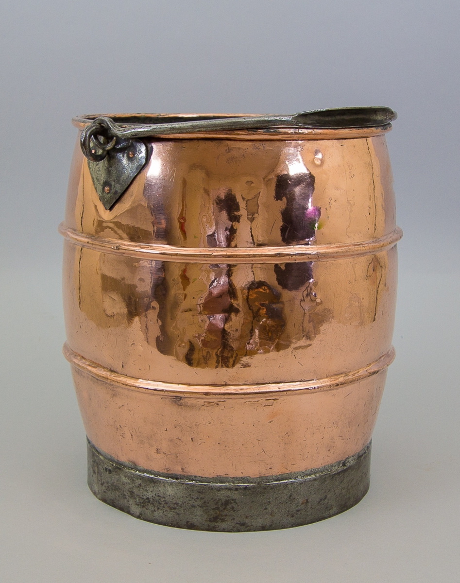 Hink av koppar och järn. Med bukig form med rullad överkant och två drivna profiler på buken. Med smidd tvärgrepe av järn fäst vid två hjärtformade fästen av järn, nitade med kopparnitar. På ett lött band av järn. Invändigt förtent.