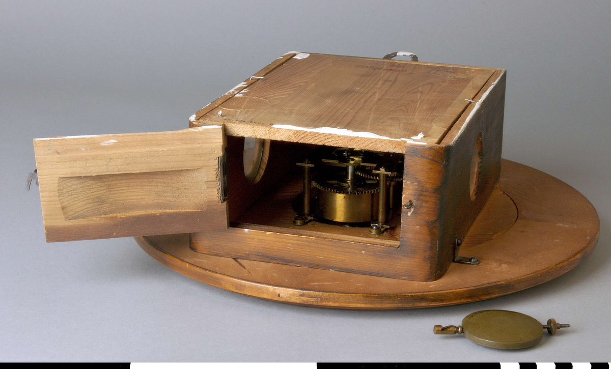 Väggur A, med löstagbar baksida B, och pendel C.
Rund urtavla med arabiska siffror och rund ram. Två visare, ett hål för uppdragning och en åttauddig stjärna med ett J och "UNGHANS" inuti. 
Urverket sitter i en låda av trä skruvad mot urtavlan. Lådan med två runda glasfönster, ett på var sida, och en nedfällbar botten. Det är märkt med samma stjärna som urtavlan och texten: WURTTEMBERG, B 25, 168. Upphängning i lådans översida. 
Anteckningar: Rep 27/765 Frej (? svårläsligt), 2209 Fm, 68 38 R, 77557 gb, gb rep 5/6-62. En stämpel i rött: L 18256.