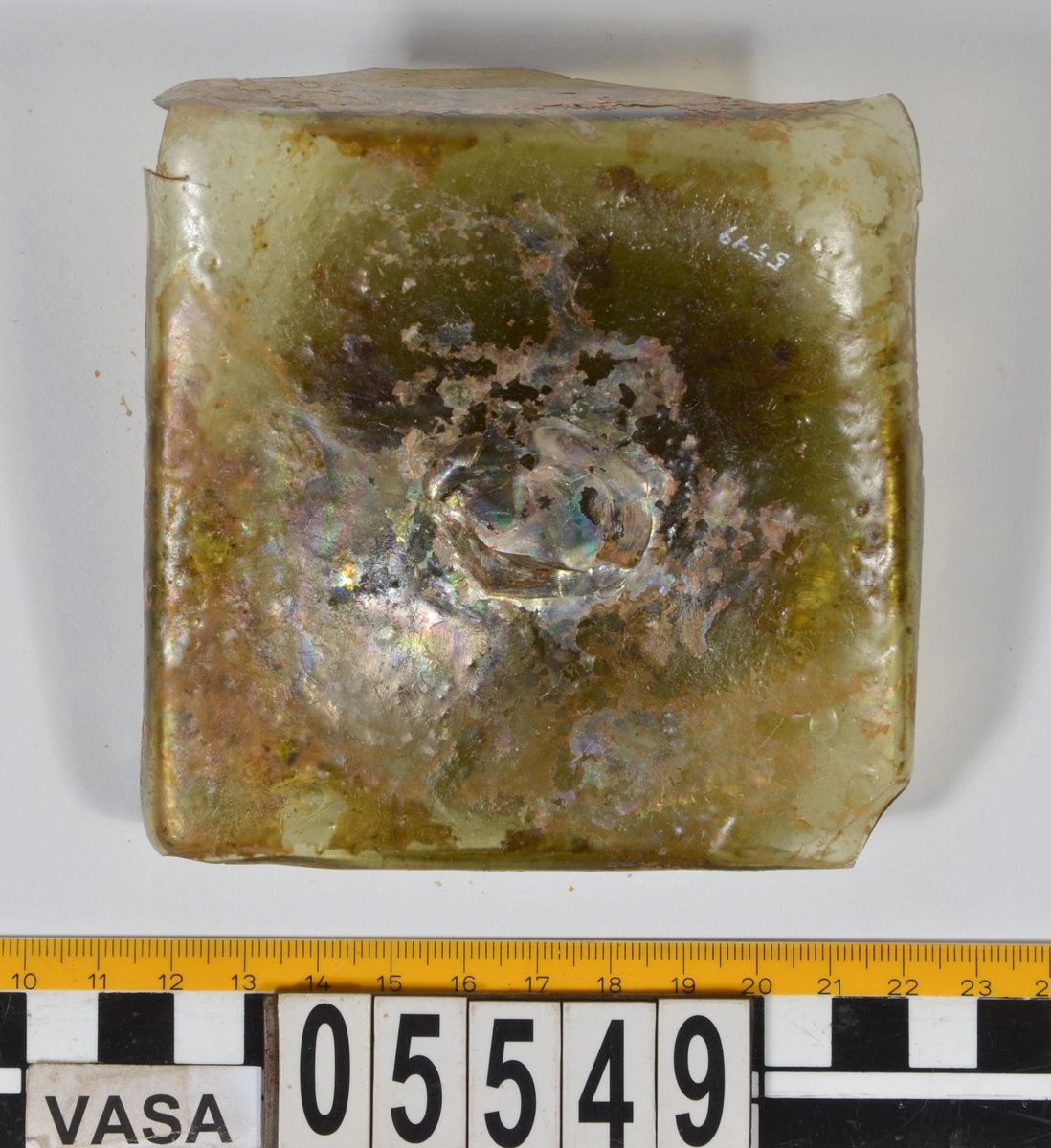 Botten till fyrsidig glasflaska. Glaset är grönfärgat.

2015: 05549a broke into three smaller pieces during handling, labled 05549 a, b, c. 05549a-d have moderate scaling.  All pieces are light green in color, and 05549d has pontil mark.