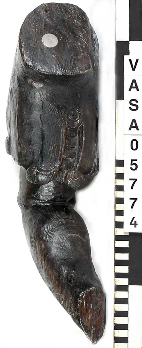 Del av skulptur. Arm till Stora krigaren på babord sida. Mycket kraftig. Bruten. Saknar hand samt en del av klädnadens ärm. Vackert snidad. Konstnären har använt sig av träets ådring för att få fram musklernas form.

Text in English: Arm belonging to sculpture. Very worn, broken.