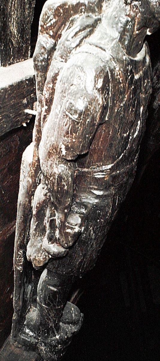 Skulptur föreställande en mansfigur med ett långsmalt och skäggigt ansikte, under en hög, slät hjälm med stora plymer. Runt hjälmen är en stålkrona trädd. Bakom huvudet skymtar ett snäckskal. Figuren är iförd en rikt ornerad rustning av thoraxmodell. Utefter figurens rygg hänger en mantel, som också draperar den vänstra axeln.

Hela figuren är frontalt framställd. Höger arm hålls lätt böjd utefter sidan, med handen fattande om ett svärdsfäste. Vänster arm är något böjd rakt ut från sidan, och handen verkar fatta tag om manteln. Kroppstyngden är jämnt fördelad på båda benen.

Figuren står på en sockel, vilken pryds av en bred och grimaserande maskaron. Sockeln är även försedd med en banderoll som tycks helt slät och utan namninskription.

Upptill är bakstycket framdraget i en kraftig "huvudplatta". Skulpturens baksida uppvisar tre snedställda, olika djupt liggande fält. Fälten, som utgör anliggningsytor, ger skulpturen en trappstegsformad profil.
Huvudplattan är delvis skadad. Svärdets klinga saknas. I övrigt är skulpturen relativt välbevarad.

Text in English: A sculpture representing a male figure with a long and narrow face that is bearded and has a moustache. On the head there is a plumed helmet on which a crown with points has been placed and behind the head a large sea shell. The figure is wearing richly decorated thorax type armour. The mantle is hanging down the back and draped over the left shoulder.

The figure faces towards the front. The right arm is slightly bent and held at the side and the hand holds a sword hilt. The left arm is slightly bent and held out from the side and the left hand seems to hold the mantle. The weight of the body is carried on both legs.

The figure stands on a plinth with a broad and grimacing mask and also has a label which is quite smooth and without any inscription.

The upper part of the back extends obliquely upwards in a powerful "head board". The sculpture''s back has three obliquely placed surfaces of different depths that are areas of attachment. The surfaces make the sculpture look like a step-ladder in profile.
The board behind the head is partly damaged and the blade of the sword is missing but otherwise, the sculpture is rather well preserved.