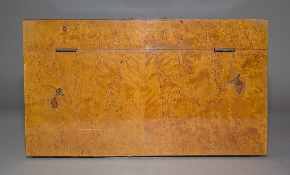 Sockerskrin (A) med lock av masurfanerat trä. Nyckelskylt och handtag av mässing. Låda (B) nertill med knopp av mässing. Skrin och låda med sinkade fogar. Locket på två gångjärn av järn. Invändigt en fast hackkniv med gångjärn av järn med svarvat handtag av trä med mässingsring. Kniven skruvad på tvärgående mellanvägg vilandes på en perforerad innerbotten. 
Med nyckel (C).